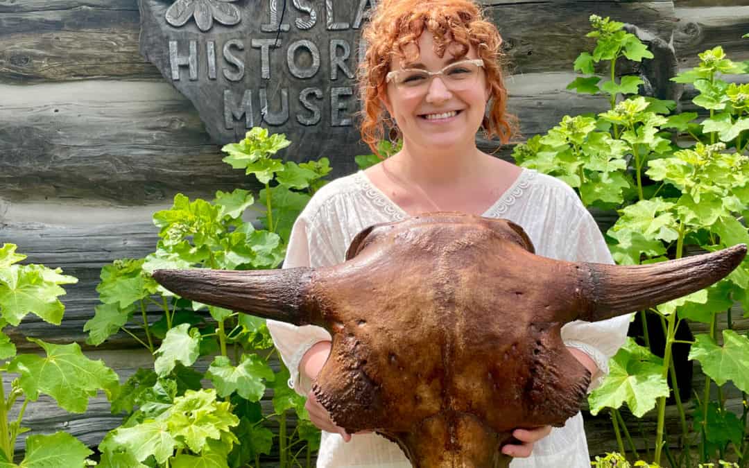 Rachel Riddle in from of Orcas Island Historical Museum holding a cast of a bison skull