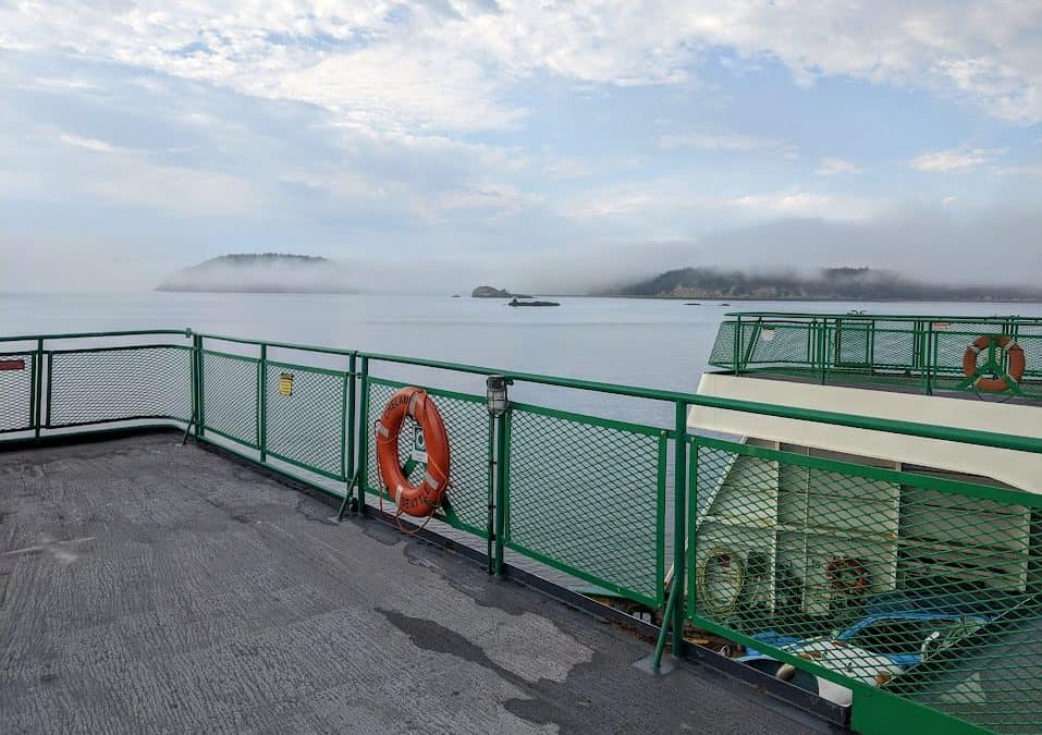 Upper deck of ferry with fog and islands in the background