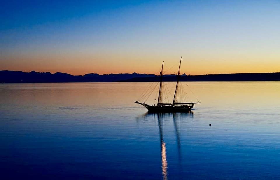 Sailboat sitting in the sea at dusk with islands beyond